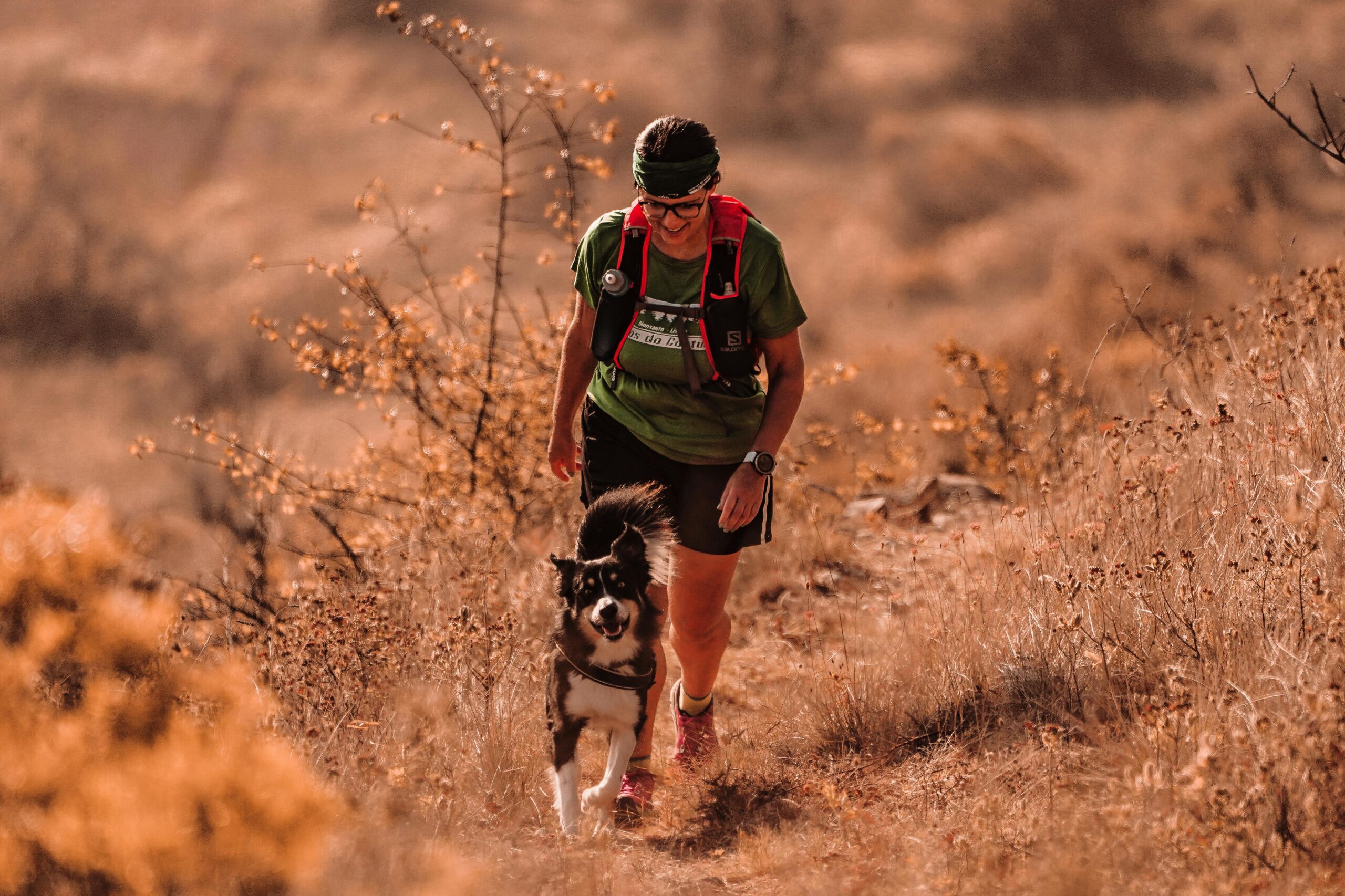 Corredora praticando canicross com Border Collie em trilha de terra batida